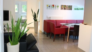 A modern living room with a black sofa, red chairs, a dining table, and a potted plant. - Comf. mod. Apartment -Anker-(120m2) in the middle of Steinhude, wallbox, parking lot, WLAN, (Wunstorf)