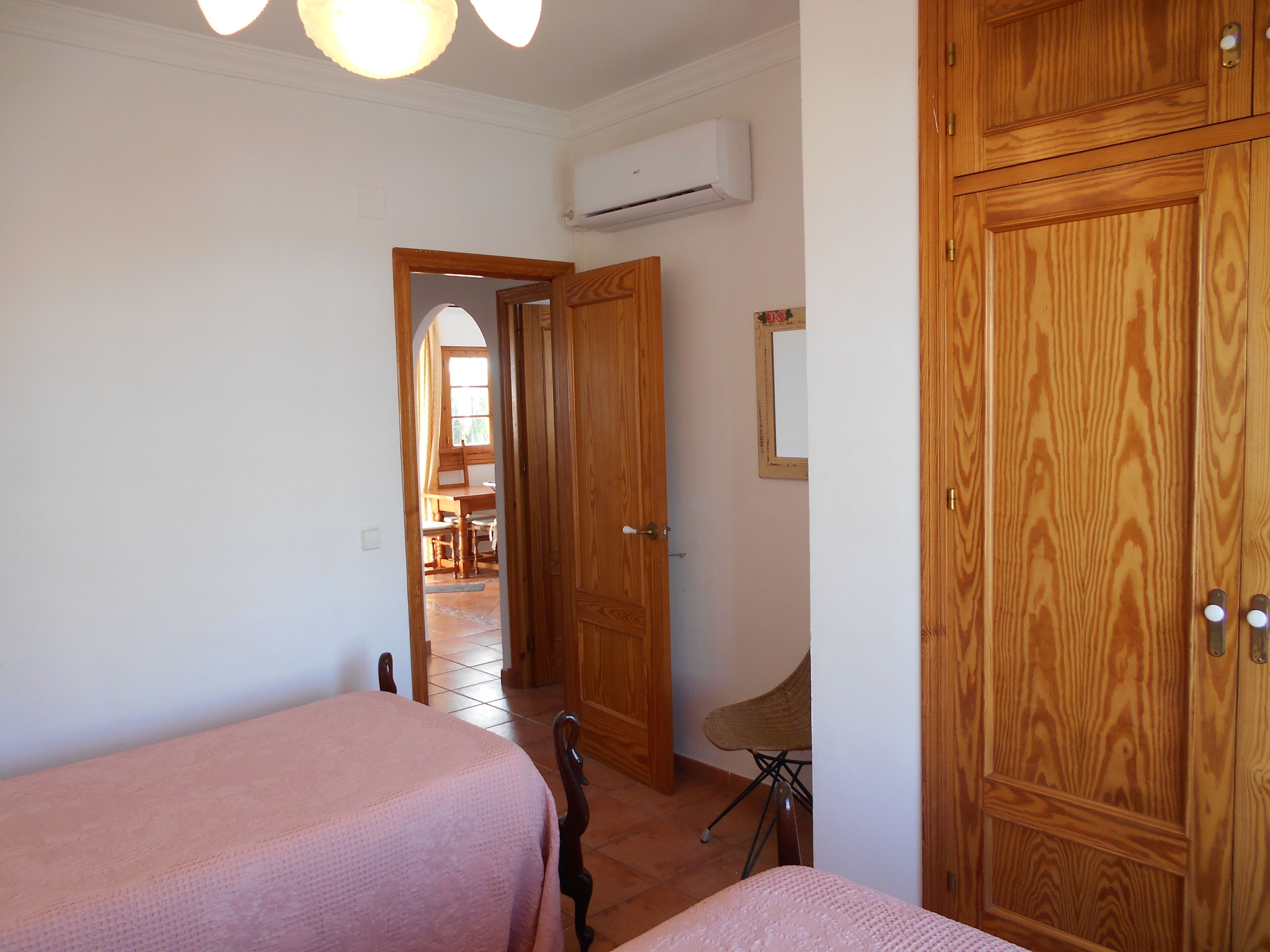 Un dormitorio con dos camas, un armario de madera y un equipo de aire acondicionado.