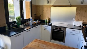 A modern kitchen with white cabinets, a stainless steel oven, and a wooden countertop. - Chalet at the foot of the slopes and 5 minutes from shops and ski school (Vars)