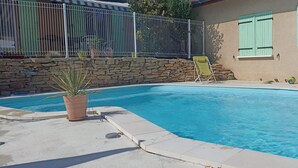 Une piscine avec un mur en pierre et une clôture en métal.
