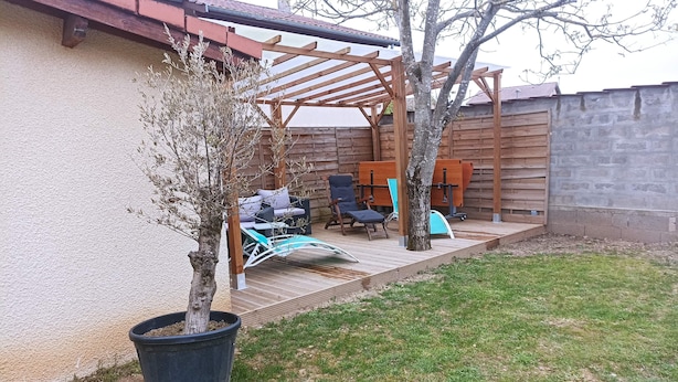 Un espace patio agrémenté d’une pergola, de mobilier d’extérieur et d’un arbre en pot.