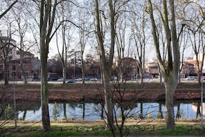 A park with a calm lake, surrounded by leafless trees and buildings in the background. - Apartment Toulouse Centre Canal to Brienne (Toulouse)