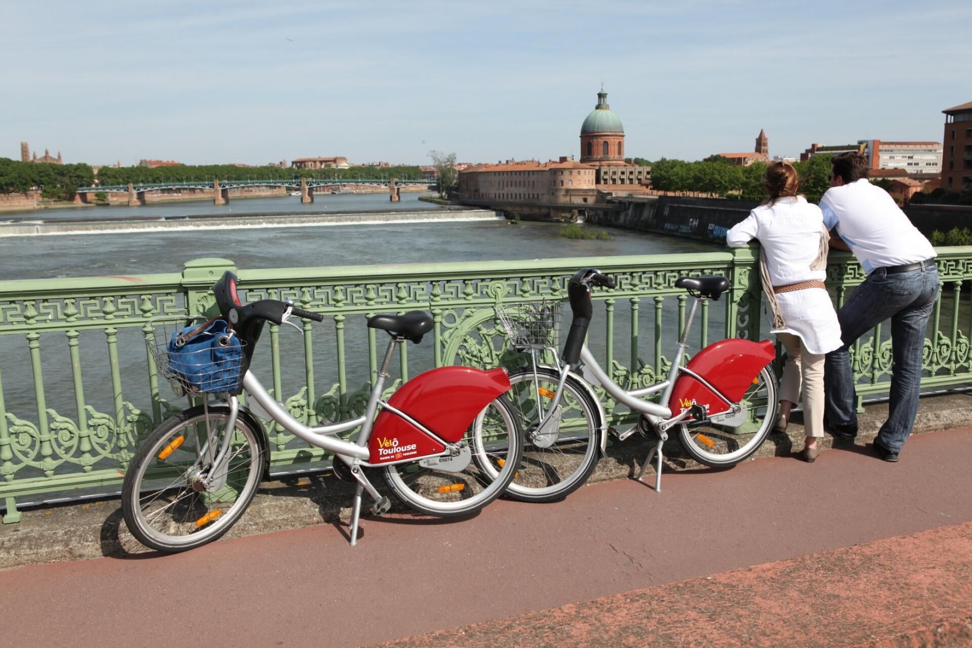 Un puente con dos bicicletas estacionadas al lado, con vista a un río y edificios al fondo.