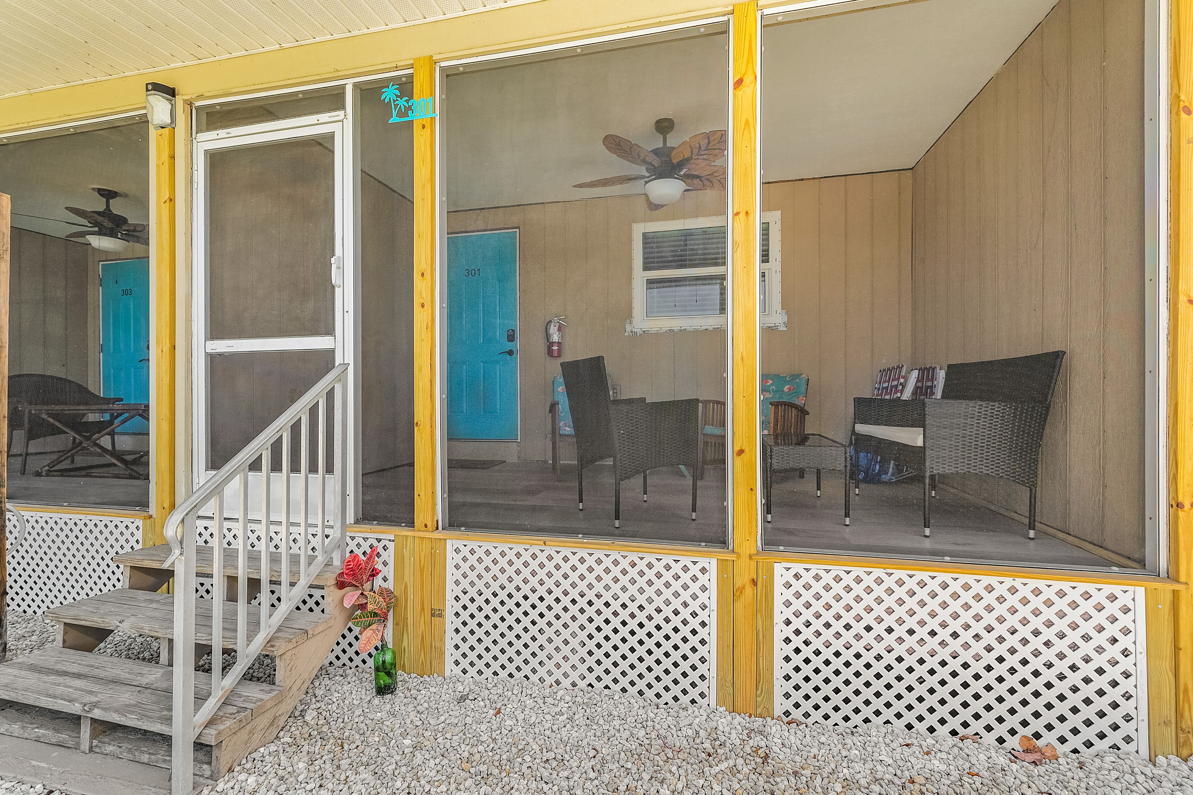 Ein überdachter Balkon mit Holzgeländer, einer blauen Tür und einem Deckenventilator.