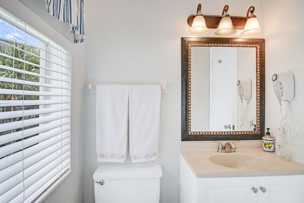 A bathroom with a toilet, a sink, and a mirror.