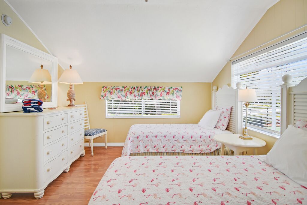 A bedroom with two beds, a dresser, a chair, and a small table.