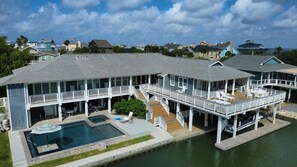 Une grande maison située au bord de l’eau, dotée de plusieurs terrasses, d’une piscine et d’un quai.