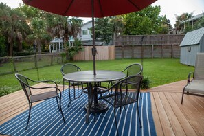 A deck with a table and chairs, surrounded by a wooden fence and a grassy yard. - 2 Blocks to Beach • Dog-Friendly 2BR • Private Downstairs Retreat • Fenced Yard (Isle of Palms)