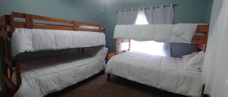Una habitación con dos literas, un ventilador de techo y una ventana con cortinas.