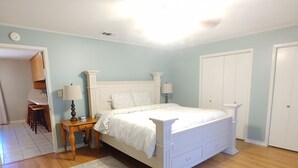 Une chambre avec un lit blanc, un plancher en bois et des murs bleu clair.