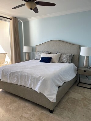 A large bed with a headboard, two bedside tables with lamps, and a ceiling fan.