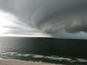 A coastal scene with a large, dark storm cloud over the ocean.