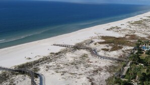 Ein Strand mit einer Holzpromenade, Sanddünen und freiem Blick auf den Ozean.
