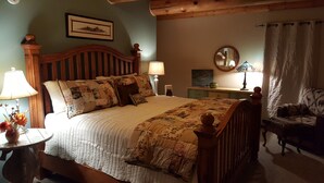 Une chambre à coucher avec un lit en bois, une table de chevet, une chaise et une lampe.