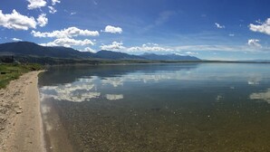 Un lac paisible aux eaux claires, où le ciel et les montagnes lointaines se reflètent.