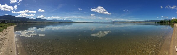 A calm lake with clear water reflecting the sky and mountains in the distance. - Where beautiful scenery is unavoidable! Fly-fishing, hiking/family time w/pets! (Ennis)