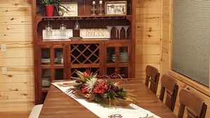 Une salle à manger en bois avec une longue table, des bancs et un lustre.