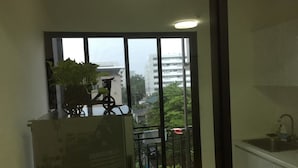 A balcony with a potted plant, a bicycle, and a view of buildings and trees. - ICONDO Ngamwongwan 1B by Tanny (Nonthaburi)