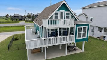Een tweelaags huis met balkon, overdekte veranda en voortuin.