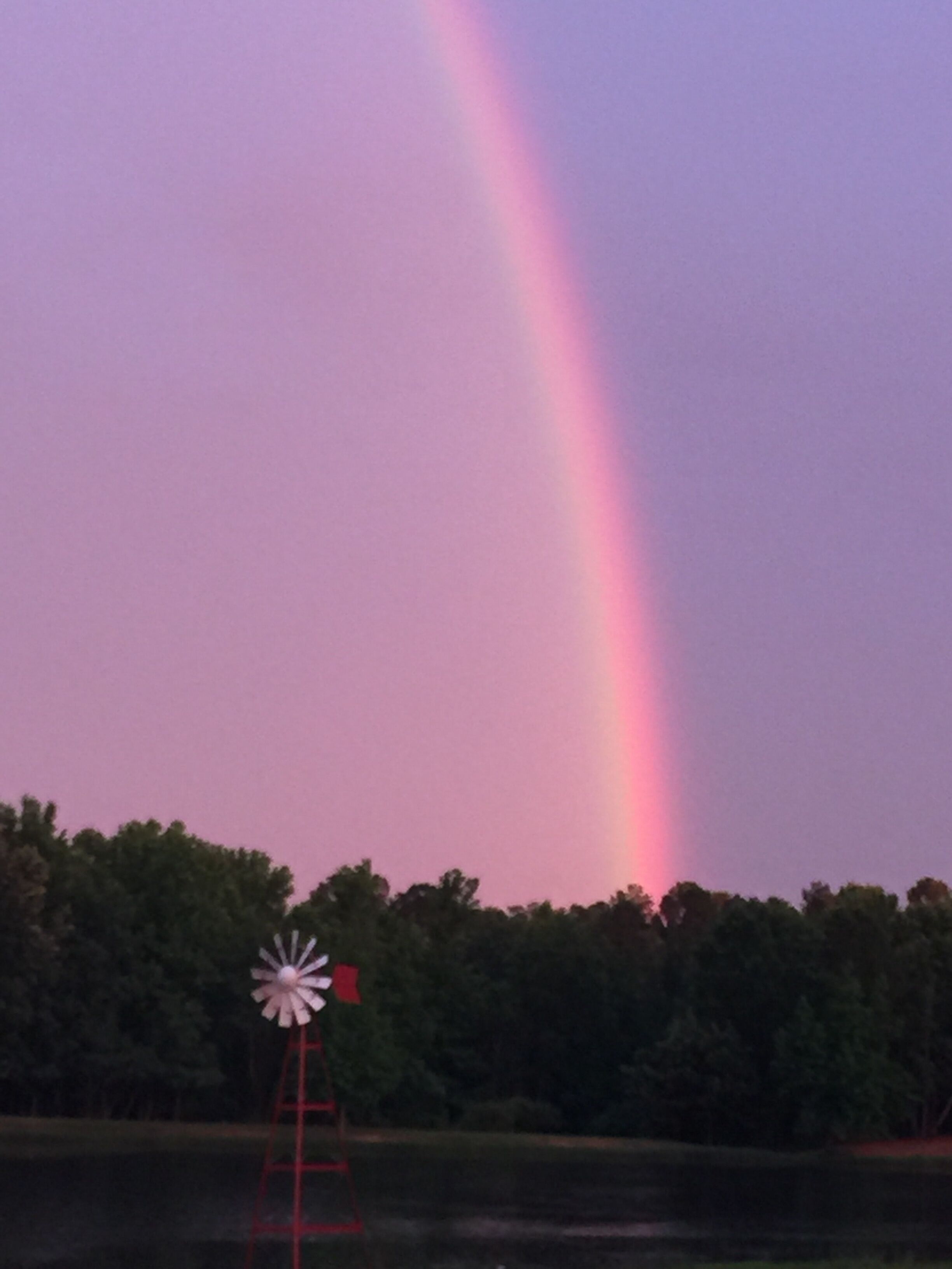 Un moulin à vent avec un arc-en-ciel en arrière-plan.