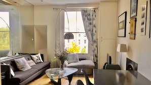 A modern living room with a sofa, a glass coffee table, and a dining table.