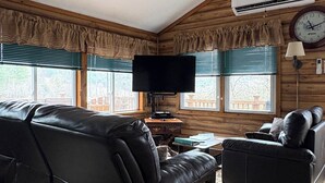 A cozy living room with a sofa, a chair, a flat-screen TV, and a ceiling fan. - Cooperstown Dreams Park, All Star Village & Hall of Fame cottage rental. (Milford)