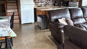 A modern kitchen with wooden beams, a dining area with a table and chairs, and a leather sofa. - Cooperstown Dreams Park, All Star Village & Hall of Fame cottage rental. (Milford)