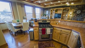 Una cocina con armarios de madera, una estufa y un comedor con sillas y una mesa.