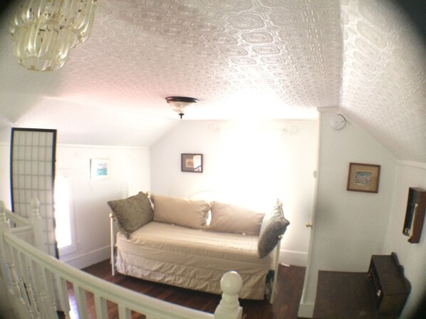 A room with a bed, a door, a staircase, and a ceiling light.