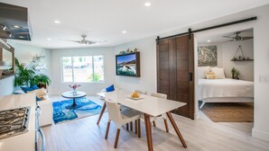 Un salon moderne avec une table à manger, un canapé et un grand téléviseur.