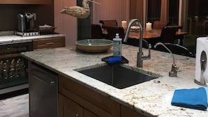 Una cocina moderna con encimera de granito, electrodomésticos de acero inoxidable y una escultura decorativa de un pájaro.
