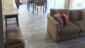 Amplia sala de estar con mesa y sillas de comedor, un sofá y una cesta de mimbre.