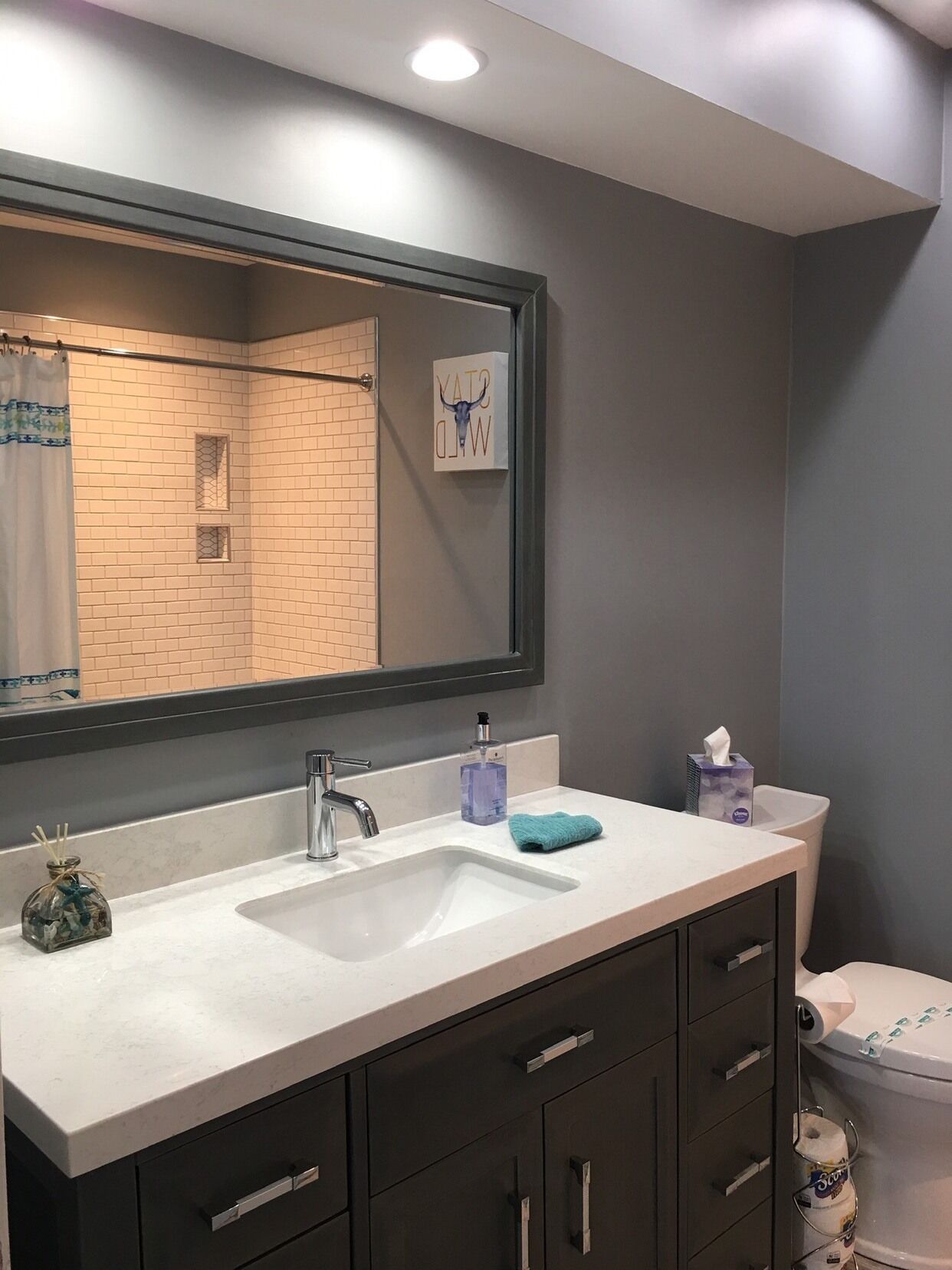 A modern bathroom with a large mirror, a sink, and a toilet.