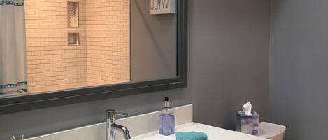 A modern bathroom with a large mirror, a sink, and a toilet.