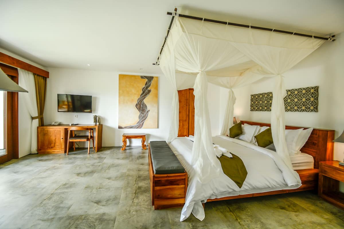 Un dormitorio con cama con dosel, un escritorio con silla, un televisor y obras de arte en las paredes.