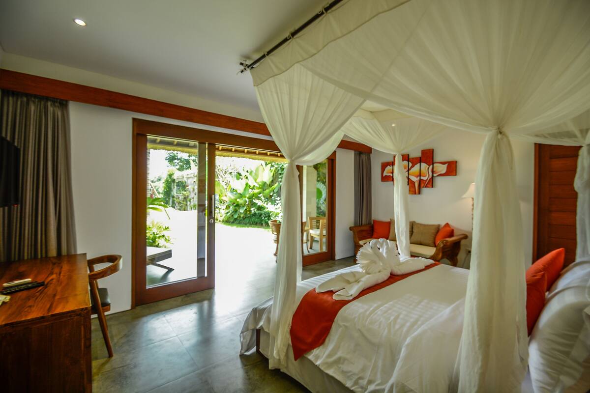 Un dormitorio con una cama grande, un escritorio de madera y vistas al exterior.