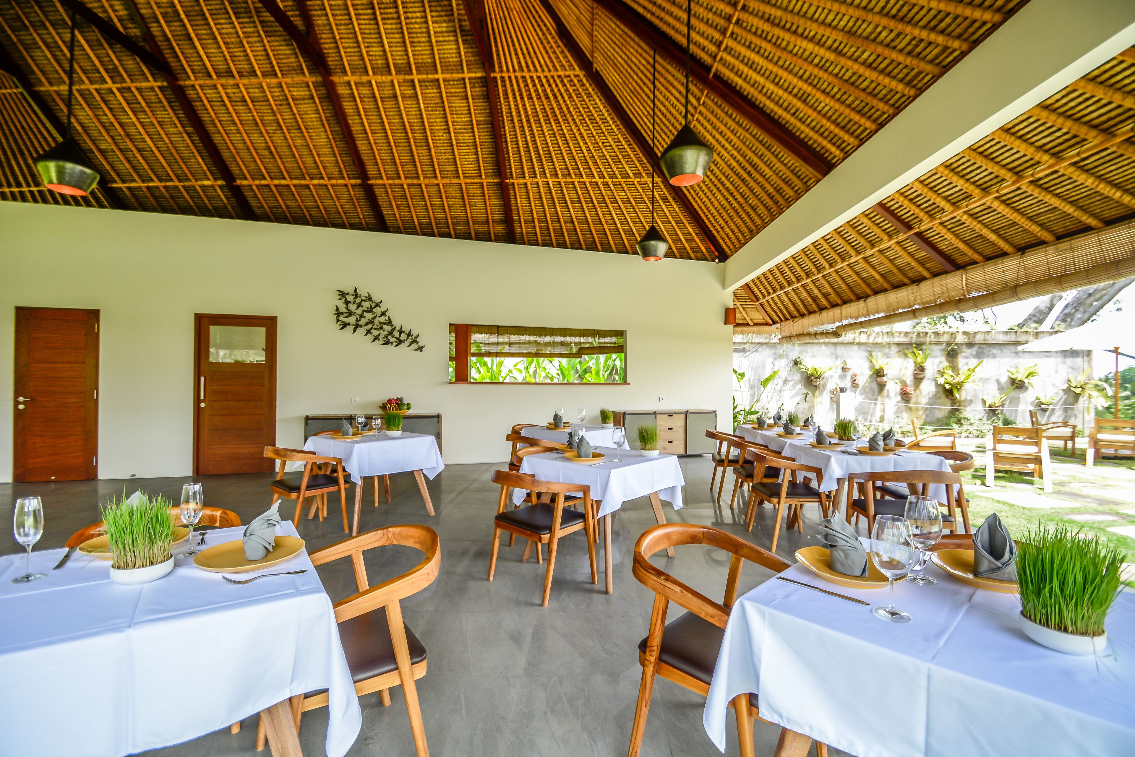 A restaurant with multiple tables, each set with plates, cutlery, and glasses.