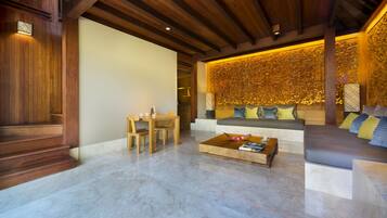 A spacious living area with a wooden ceiling, a sofa with cushions, a coffee table with books, and a wall with intricate carvings.