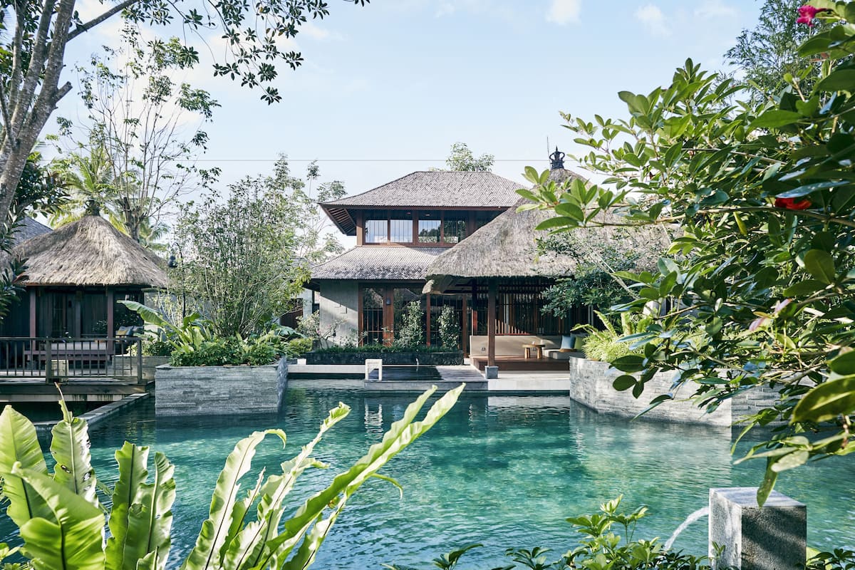 A resort with a pool, thatched-roof structures, and lush greenery.