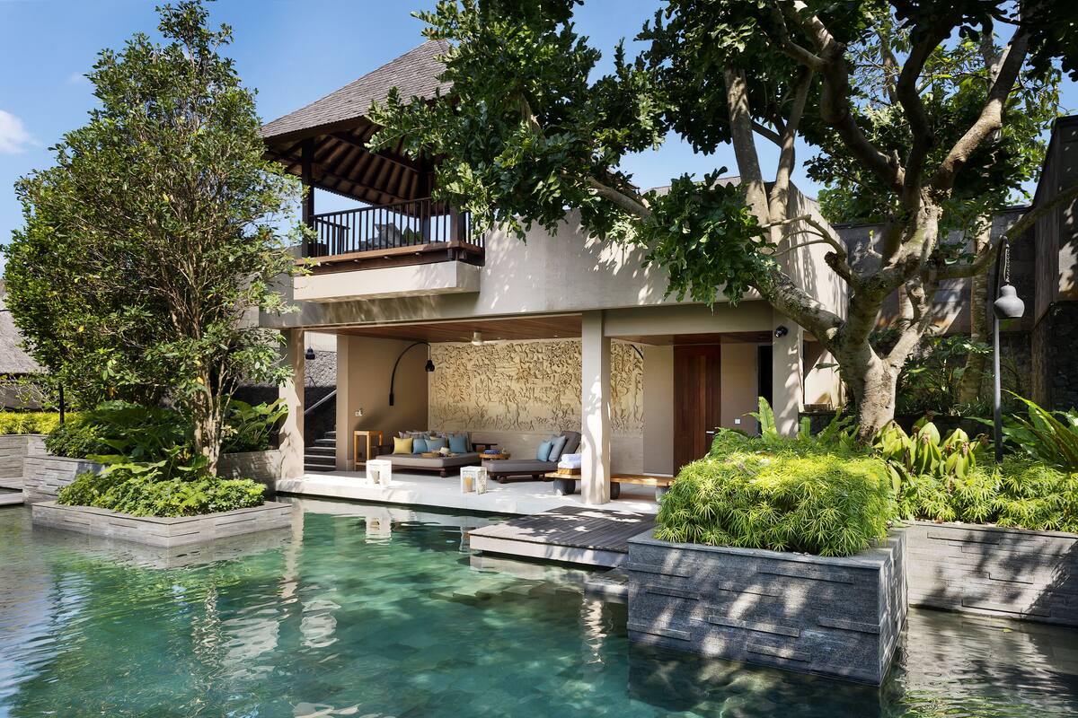 A modern house with a pool, outdoor seating, and lush greenery.