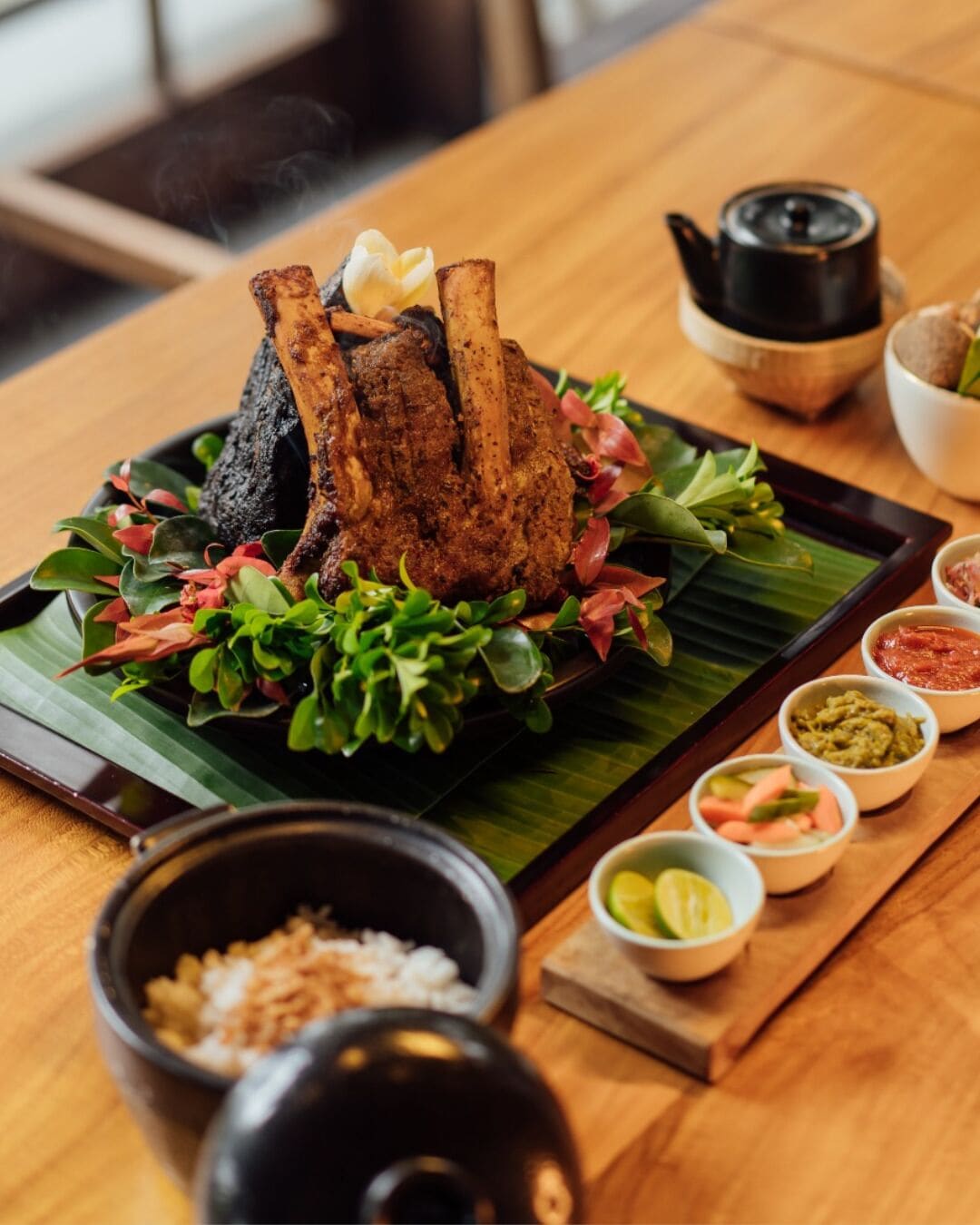 A table with a roasted duck centerpiece, a teapot, and various condiments.