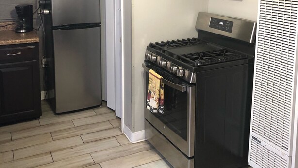 A compact kitchen with a stainless steel refrigerator, microwave, stove, and oven. There are hanging kitchen utensils and a 'Kitchen' sign on the wall. - No cleaning fee!!!  EV Charging Property in Exclusive Neighborhood! (El Paso)