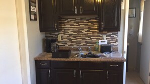 A modern kitchen with dark cabinetry, a tiled backsplash, and a granite countertop. - No cleaning fee!!!  EV Charging Property in Exclusive Neighborhood! (El Paso)