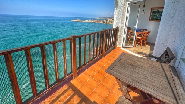 Un balcon avec vue sur la mer, une table en bois et une chaise.