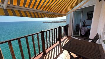 Un balcón con vista al mar, una mesa de madera y una silla.