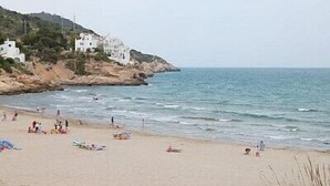 Une plage bordée de bâtiments blancs sur une colline, une plage de sable et une mer calme.