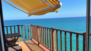 Un balcone con vista sull'oceano, una ringhiera in legno e un tavolo con sedie.