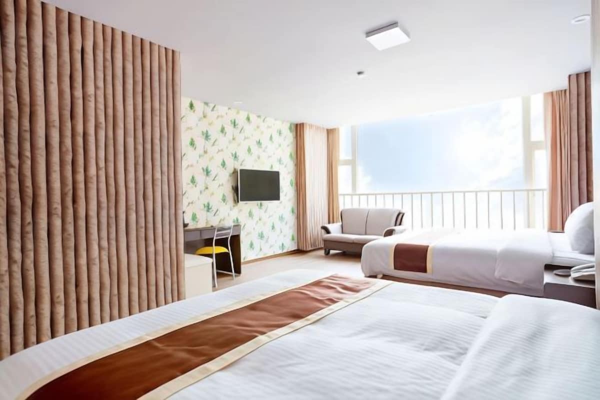 Habitación de hotel con dos camas, un escritorio, una silla y un televisor.