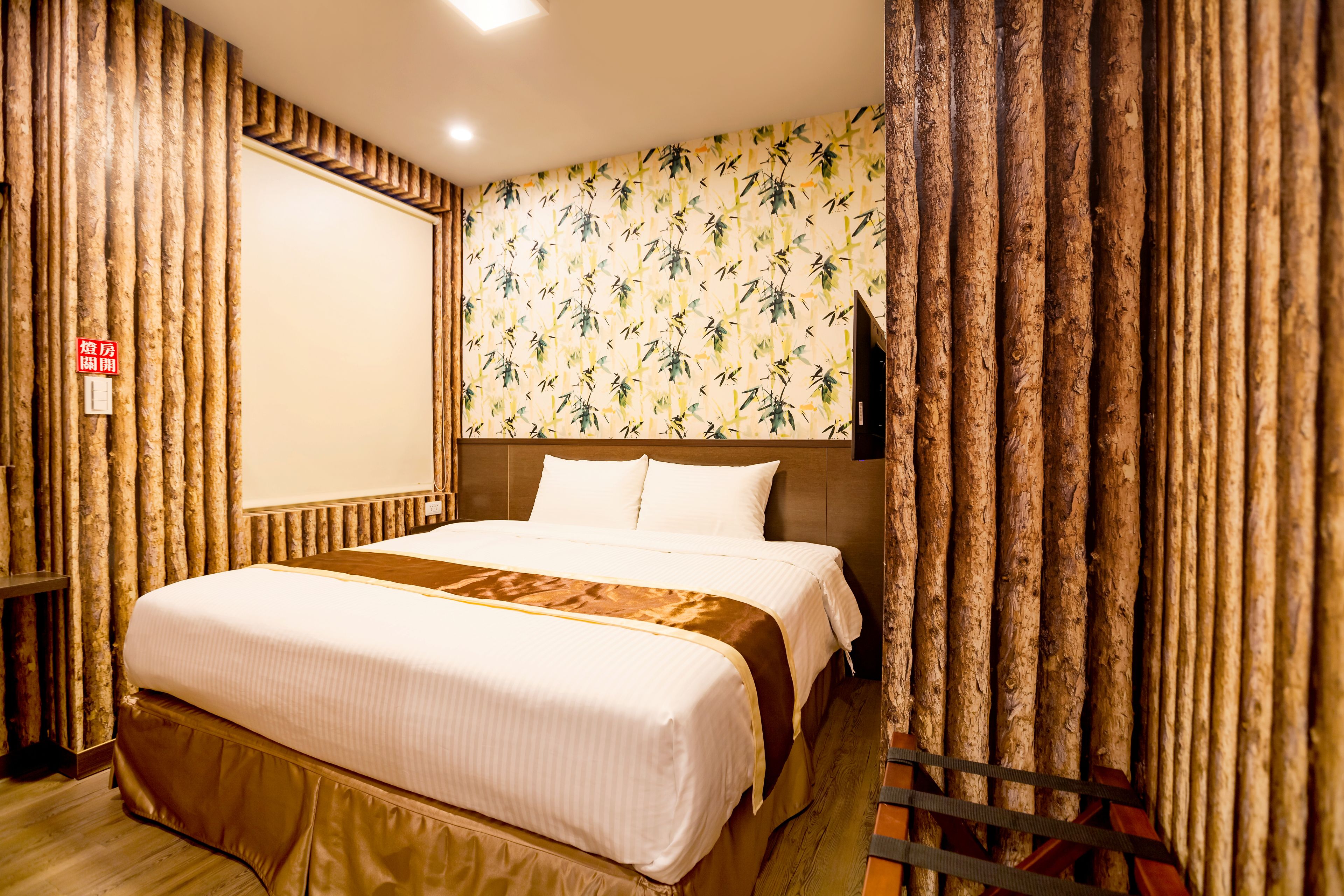 A hotel room with a large bed, wooden paneling on the walls, and a bamboo-patterned wallpaper.