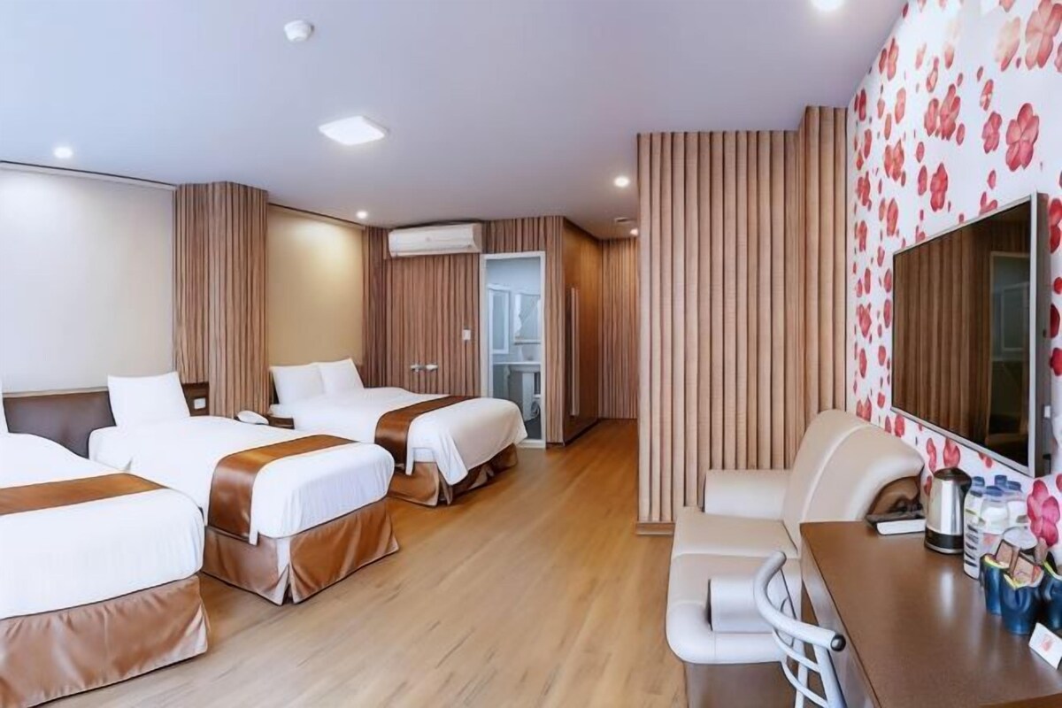 Een hotelkamer met drie bedden, een zithoek en een grote spiegel.